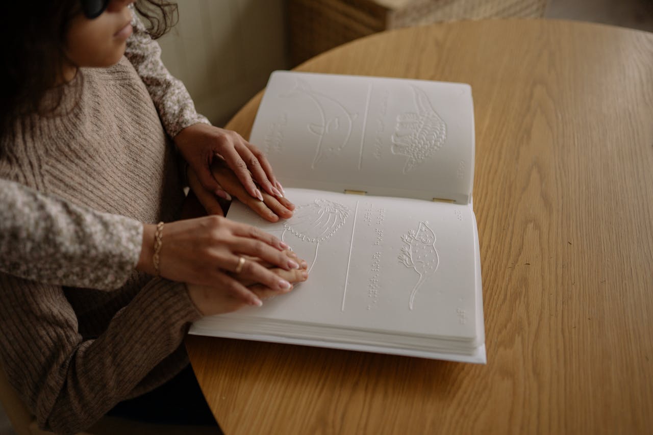 Services A child reads a Braille book with guidance, focusing on learning and touch.